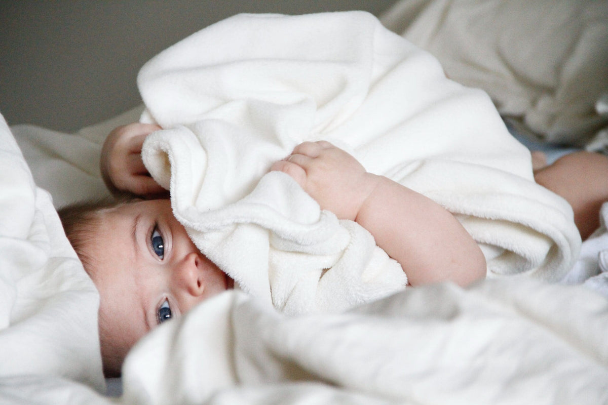 Baby lying under a soft white blanket